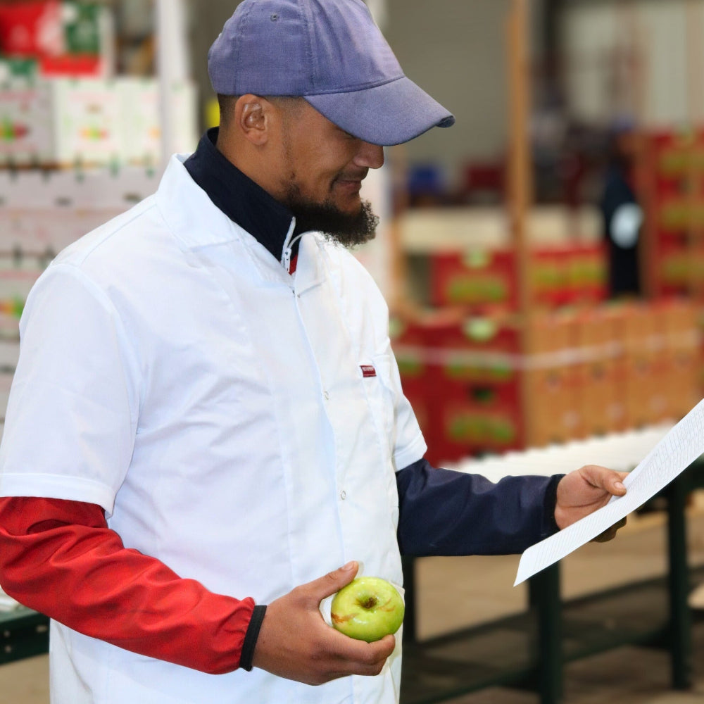 Person holding an apple and a piece of paper in a warehouse setting