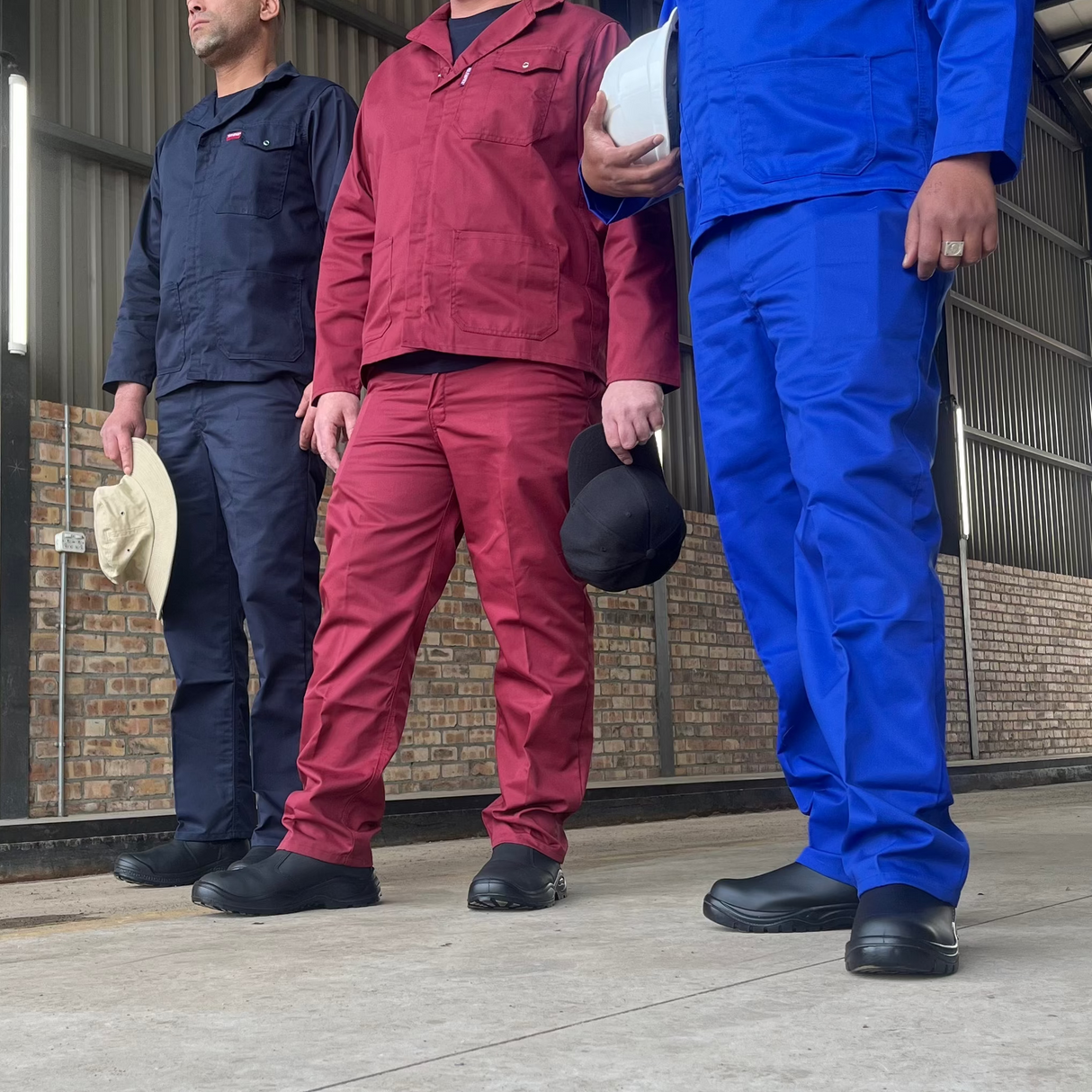 Three men in workwear standing in a warehouse.