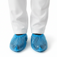 Blue shoe covers worn with white pants on a white background