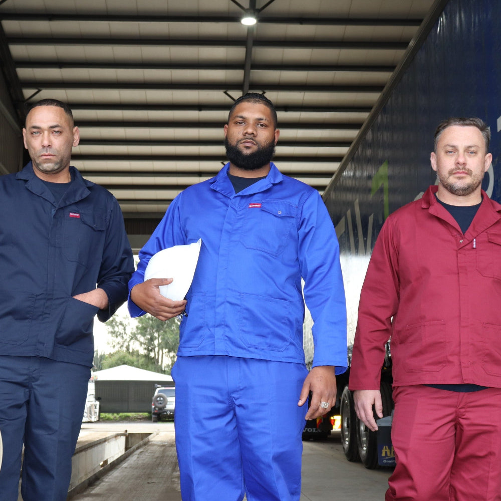 Three men in work uniforms walking in front of a truck with branding.