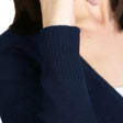 Close-up of a person wearing a navy blue sweater or cardigan with a blurred white background